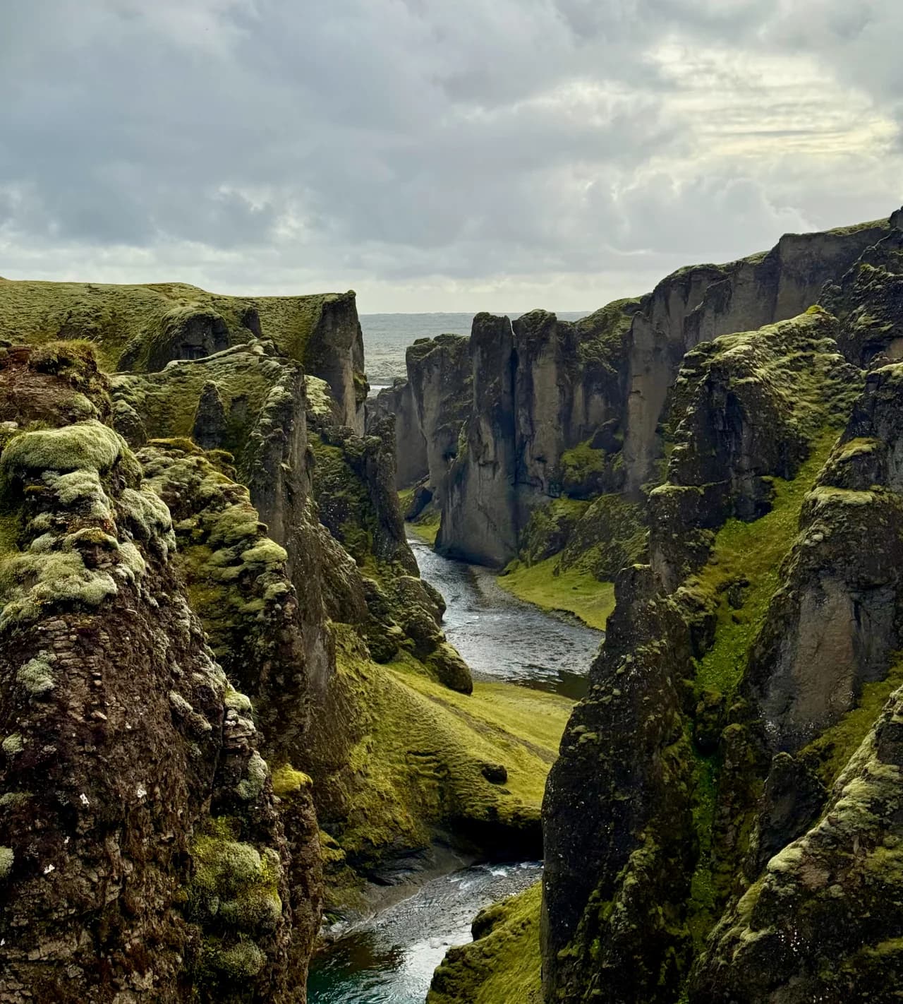 Braided glacial rivers crossing a vast black sand plain beneath a cloudy Icelandic sky.